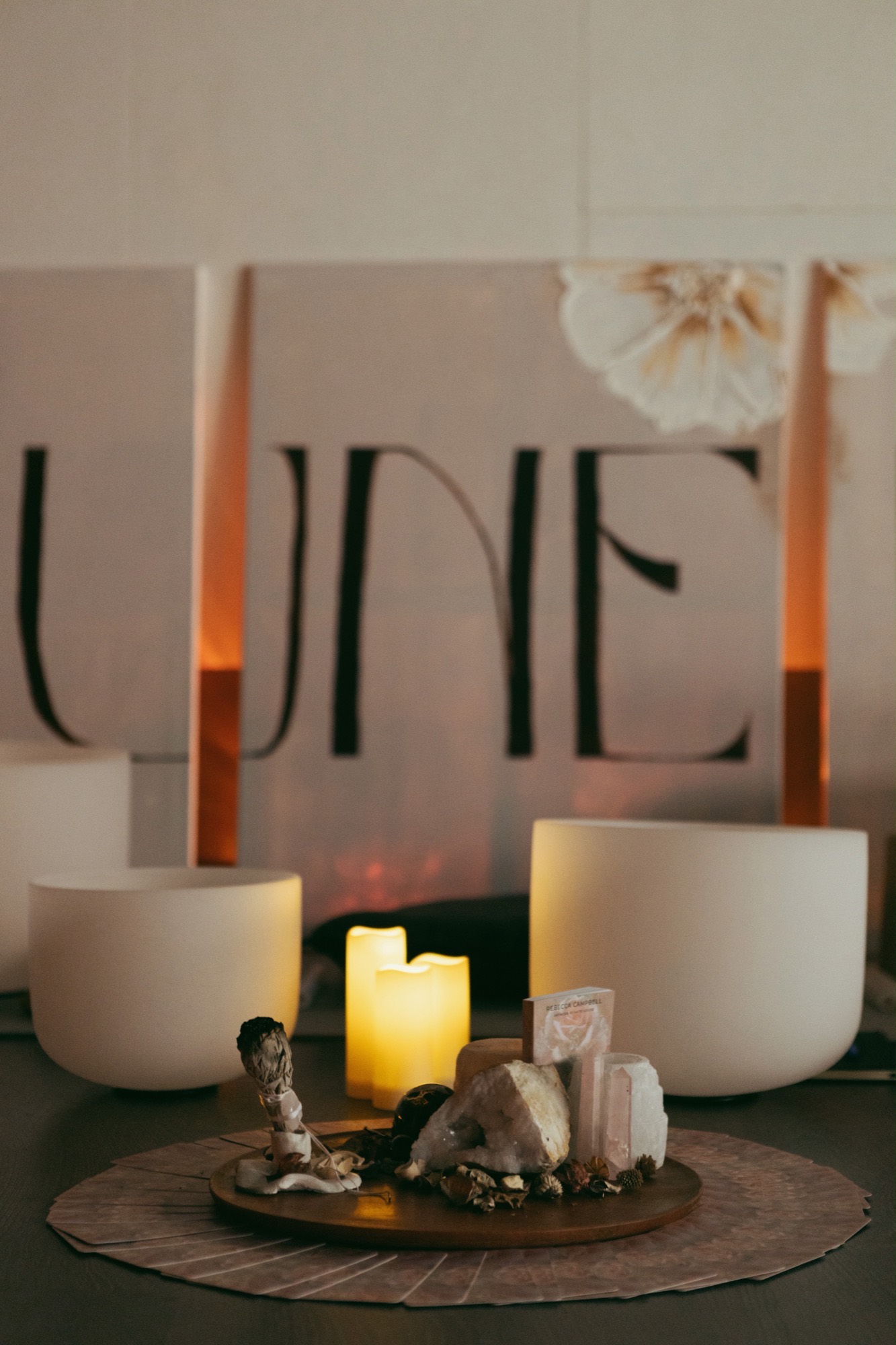 The Tune In ritual altar with crystals, a candle, and crystal singing bowls in warm light